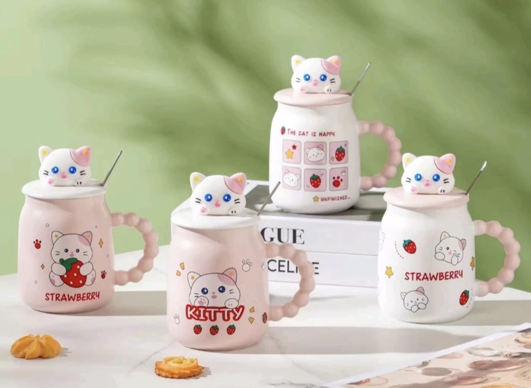 Cuatro tazas mug de cerámica rosa y blanca con gatitos 3D en la tapa, diseño de fresas y texto 'Strawberry' o 'Kitty', con asas enrolladas y cucharas incluidas.